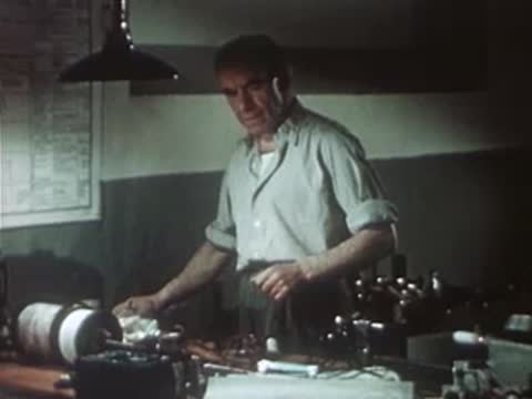 Worker assembling electrical equipment on a workbench in a vintage workshop.