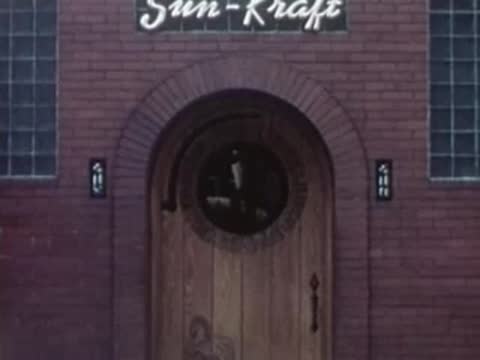 Arched wooden doorway of the Sun-Kraft building with a sign above it.