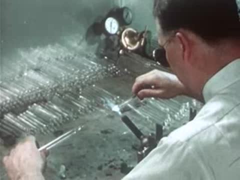 Technician working with a glass tube using a torch in the workshop.