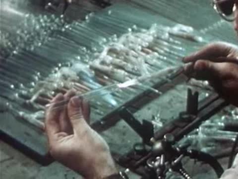 Craftsman pulling and sealing a heated quartz glass tube.