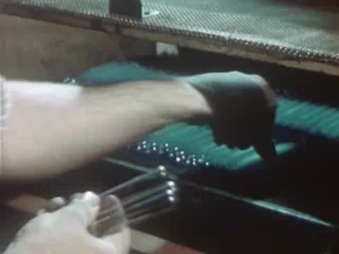 Worker organizing glass tubes on a factory production rack.