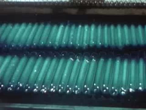 Rows of manufactured quartz tubes glowing with a greenish hue.