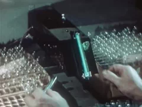 Worker testing glowing mineral sample under UV lamp in laboratory.