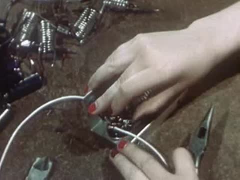 Factory worker using pliers to secure wiring inside metal electronic housing.