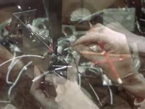 Worker soldering electronic components and wiring inside metal housing.