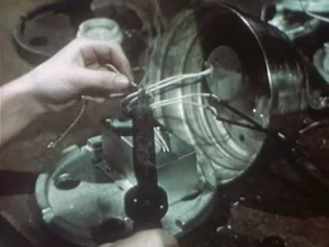 Worker wiring electrical components inside housing on factory production line.