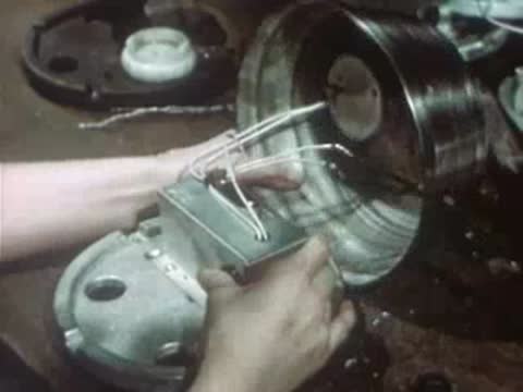 Worker closing metal housing on assembled electronic device in factory.