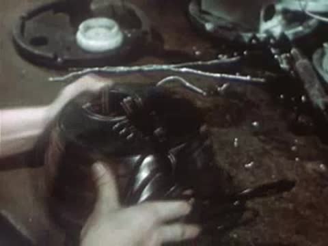 Worker attaching outer casing to assembled electrical device in factory.