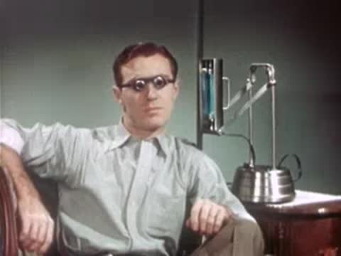 Man sitting indoors wearing special glasses while portable lamp operates nearby.