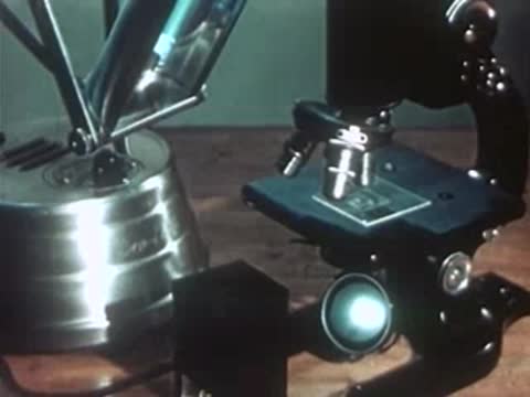 Microscope setup on table next to operating ultraviolet lamp apparatus.
