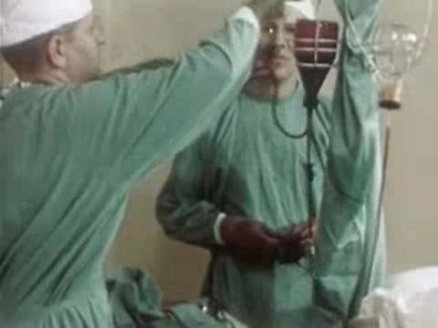 Medical personnel operating medical equipment in a hospital operating room, 1940s.