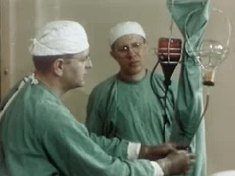 Surgeon and assistant talking in an operating room, 1940s style.
