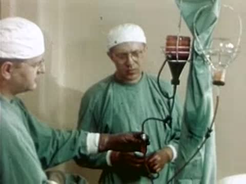 Surgeons holding and testing medical tubing in a hospital setting, 1940s.