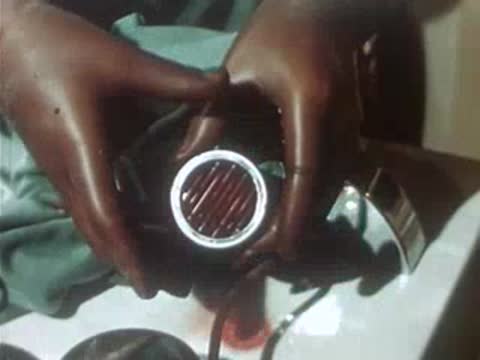 Hands in rubber gloves opening a chrome medical lamp or device.