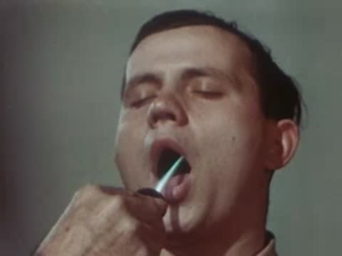 Patient having their throat examined with a medical instrument, 1940s.