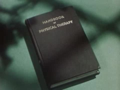 A closed book titled Handbook of Physical Therapy lies on a surface.