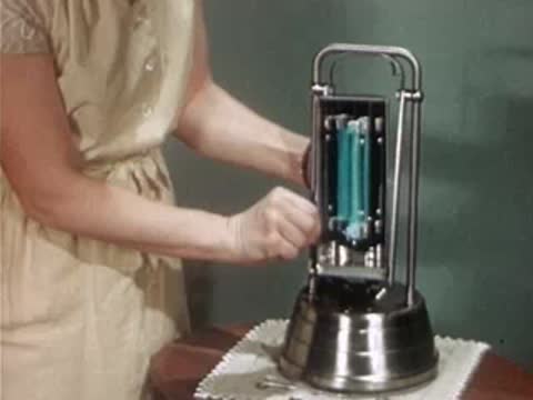 A person assembles and turns on a portable ultraviolet therapy lamp on a table.
