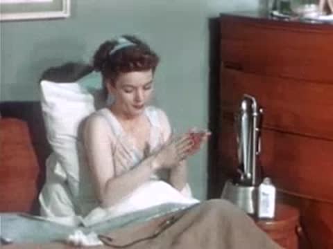 A woman sits propped up in bed, wipes her eyes, and prepares for treatment.