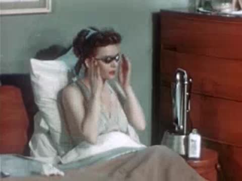 A woman in bed puts on protective goggles before an ultraviolet lamp turns on.