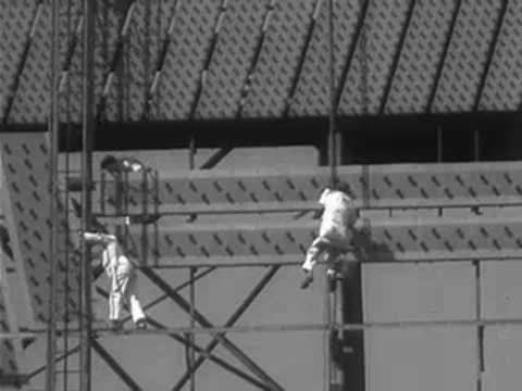 Workers maintaining a large illuminated structure against the sky.