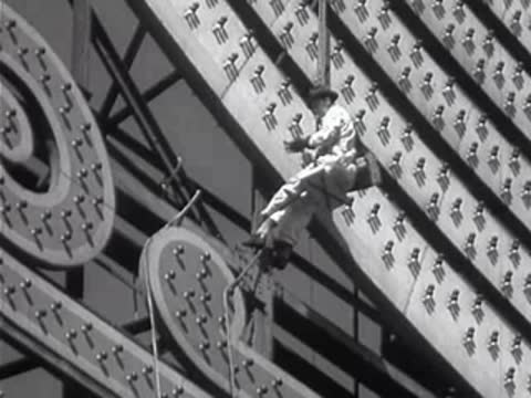 Worker suspended by ropes cleaning bulbs on a massive sign.