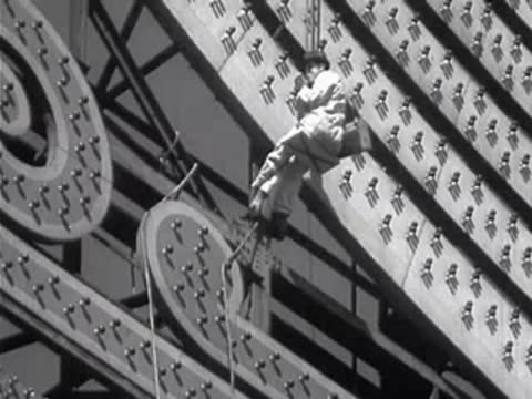 Worker cleaning lightbulbs on a massive sign structure.