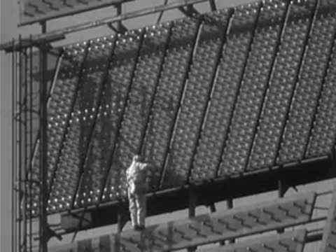 Worker maintaining lightbulbs on a large sloped billboard section.