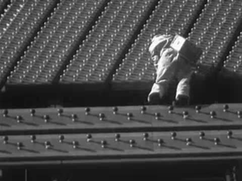 Worker walking along the ledge of a massive illuminated sign.