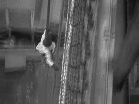 Worker suspended on ropes against a giant lettered sign.