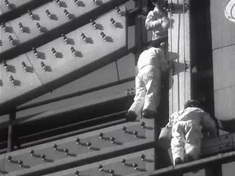 Workers on a catwalk maintaining elements of a large sign.