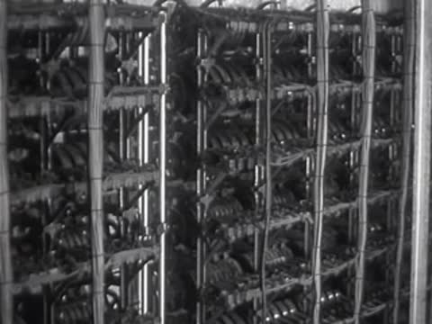 A man walking past large electrical switching equipment in a room.