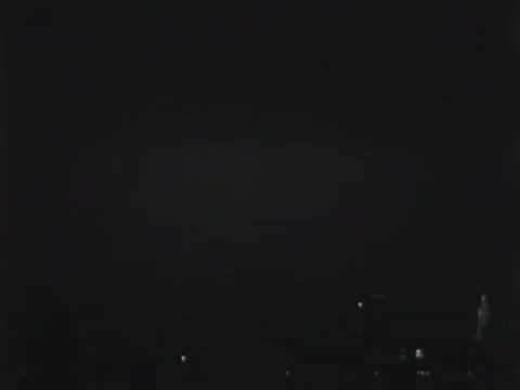 Nighttime cityscape with illuminated signs including Chevrolet and Sunkist.