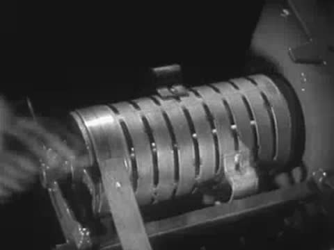 A hand operating a mechanical control drum with electrical contacts.