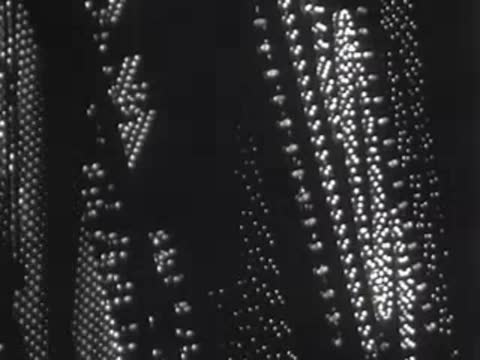 Vertical tracking shot down a tall building facade covered in lights.