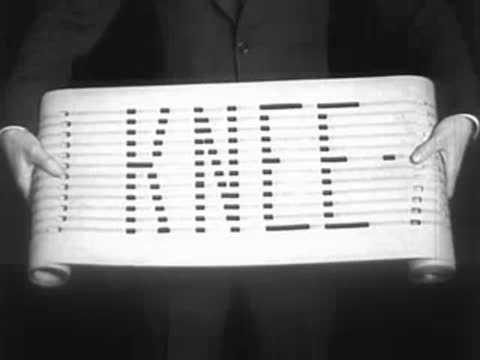 A paper scroll unfurling to display printed text with perforated characters.