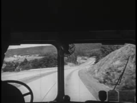 View from bus driver's seat, winding road, vintage travel.