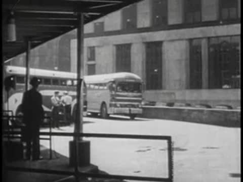 Bus arriving at terminal station, vintage vehicles and people.