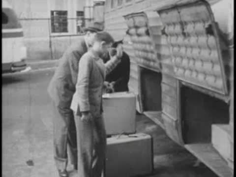 Passengers unloading luggage from bus compartment, vintage travel.