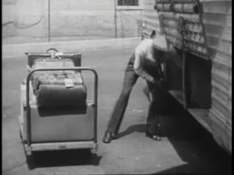 Driver loading luggage into the side compartment of a bus from a cart