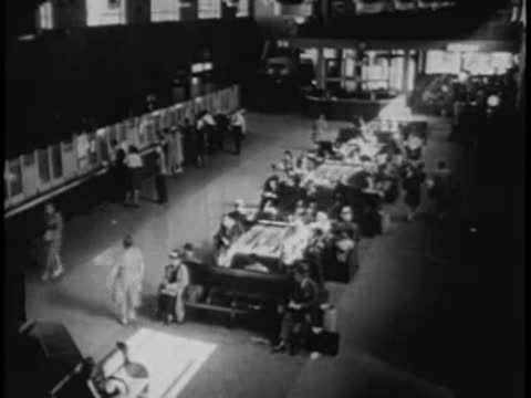 High-angle view of a large bus terminal interior with people and luggage