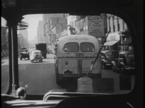View from inside the bus looking ahead through the windshield at moving traffic and vans