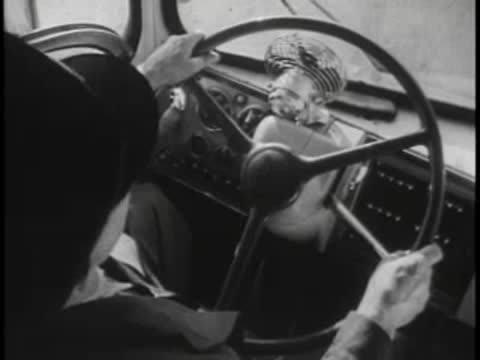 Over-the-shoulder view of a driver steering a vintage bus interior.