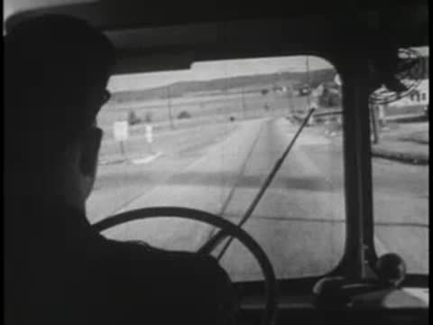 View from inside a bus looking down a rural highway through the windshield.