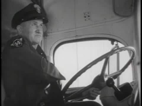 Bus driver in uniform adjusting his jacket or collar inside the cabin.