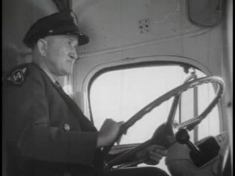 Bus driver in uniform holding the steering wheel and looking forward.