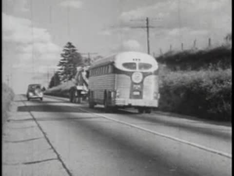 Bus driving on road, past car, countryside scenery, 1940s.