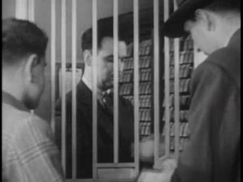 Close-up through ticket window bars of a boy talking to the clerk