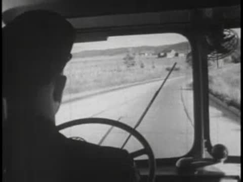 Driver's view from bus interior, winding road, steering wheel.