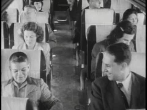 Passengers sitting inside bus, talking and looking out window.