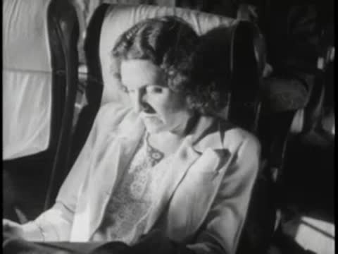 Female passenger reading book inside moving bus, daylight.